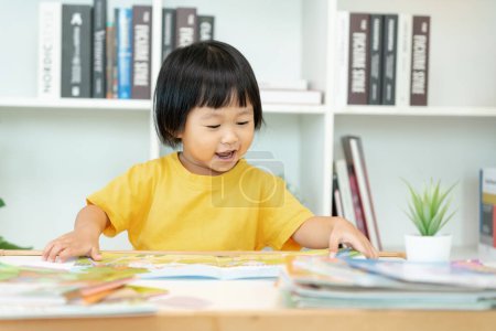 Happy Asian children relax read book at home. daughter and reading a story. learn development, childcare, laughing, education, storytelling, practice, imagine, reduce addiction mobile phon