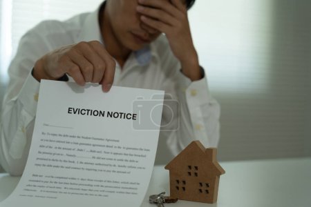 Business man is stressed due to imminent seizure of assets, debts, financial problems, loans, guarantees document with the text eviction notice, debt, property, loan, agent, bankruptcy