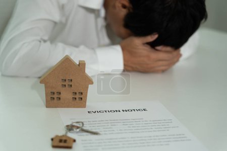 Business man is stressed due to imminent seizure of assets, debts, financial problems, loans, guarantees document with the text eviction notice, debt, property, loan, agent, bankruptcy