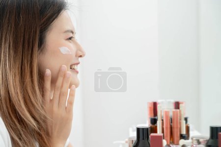 Schöne asiatische Frau Lächeln verwenden Creme für gute Haut. Gesicht einer gesunden Frau Creme und Make-up auftragen. Werbung für Hautcreme, Anti-Falten, Babygesicht, Bleaching, Feuchtigkeitscreme, Straffung der Poren Serum