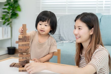Asia Happy single mother playing learning games janga with the little girl. Funny family is happy and excited in the house. ther and son having fun spending time together. holiday, weekend, vacant