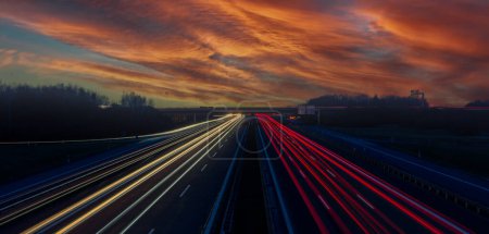 Auto fährt bei Sonnenuntergang auf Autobahn in den Himmel
