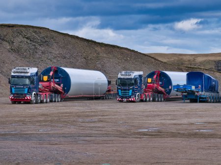 Photo for Lorries waiting to take wind turbine support tower sections to their construction sites. Work underway to build the Viking Wind Farm in Shetland, UK. - Royalty Free Image