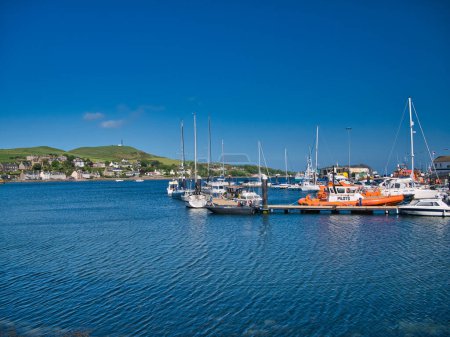 Foto de Barcos en Campbeltown Marina en la península de Kintyre, Escocia, Reino Unido. Tomado en un claro día soleado con un cielo azul y sin nubes. El barco piloto naranja aparece a la derecha. - Imagen libre de derechos