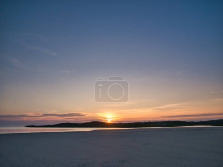 Photo for Sunset over the deserted Ardroil Sands (Uig Sands) on the Isle of Lewis in the Outer Hebrides, Scotland, UK. Taken with a mainly clear sky and low clouds over the horizon. - Royalty Free Image