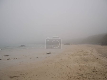 Photo for A single person on the Port of Ness Beach on the Isle of Lewis, Outer Hebrides, Scotland, UK. Taken on a  dreich day - wet and misty. - Royalty Free Image