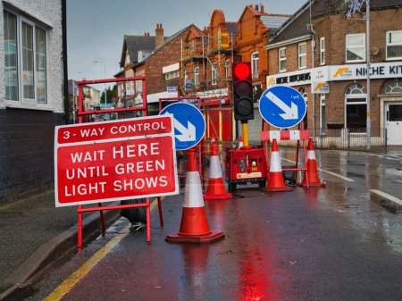 Photo for Wirral, UK - Dec 31 2023: A three way traffic control system in place at roadworks in an urban area of UK. The image shows signs, bollards and the controlling traffic lights. - Royalty Free Image