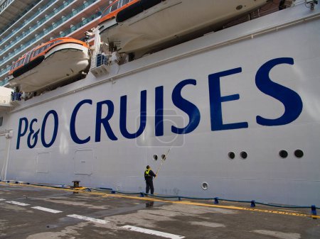 Photo for Philipsburg, St Maarten - 24 Jan 2024: A worker pressure washes the white hull and blue brand logo of a P and O cruise liner in the Caribbean. - Royalty Free Image