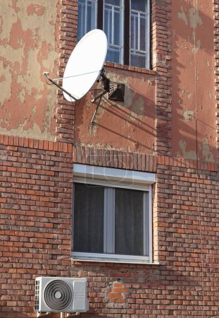 Photo for Satellite dish and air conditioner on the wall of an old apartment building - Royalty Free Image