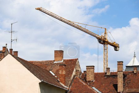 Photo for Tower crane behind roofs of buildings in the city - Royalty Free Image