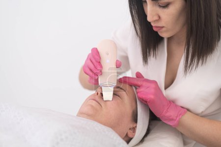 Téléchargez les photos : Femme d'âge moyen recevant échographie cavitation visage peeling et nettoyage. Cosmétologie et soins du visage - en image libre de droit
