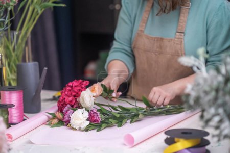 Téléchargez les photos : Expert décorateur de fleurs en utilisant ses mains pour créer un beau bouquet de roses de près. atelier plus lent - en image libre de droit