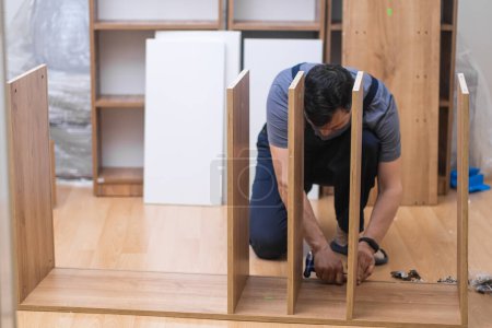 Fixing furniture business skilled handyman screwing nails into cabinet with professional instrument cupboard made of high-quality wood materials for stylish interior design