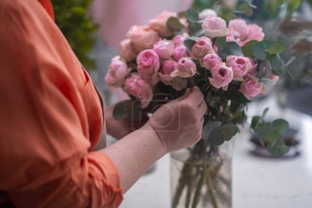 Téléchargez les photos : Artiste floral professionnel façonnant soigneusement un superbe rose arrangement.floral studio de conception. - en image libre de droit