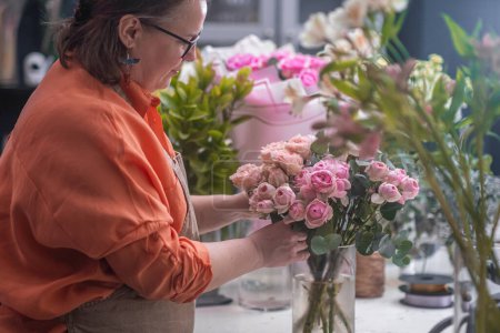 Téléchargez les photos : Fleuriste talentueux concevant un bel arrangement de roses roses avec précision et soin, profession de décorateur floral. - en image libre de droit