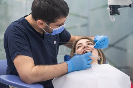 Téléchargez les photos : Soins dentaires dans une clinique moderne axée orthodontiste regardant les dents de la patiente à l'aide d'outils professionnels spécialiste qualifié préparer la femme à la correction des morsures - en image libre de droit