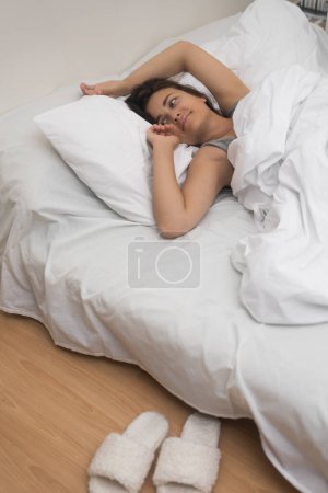 healthy woman sleeps on bed with light linen enjoying sleep near stylish home bedroom