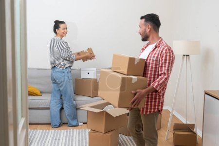 Téléchargez les photos : Propriété : couple sourit briller comme ils emballent des boîtes pendant le déménagement dans leur maison hypothéquée - en image libre de droit