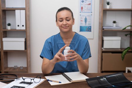 doctor in blue uniform holding jar with pills talking to patient online consultation in clinic. 