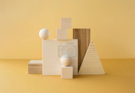 Composición geométrica horizontal equilibrada de diferentes figuras de madera sobre fondo amarillo.