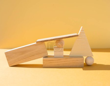 Varios objetos de madera tridimensionales sobre fondo amarillo. Concepto de equilibrio, arte y diseño.