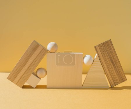 Geometrische Figuren Stillleben Komposition. Verschiedene dreidimensionale Holzobjekte auf gelbem Hintergrund. Balance, Kunst und Designkonzept.