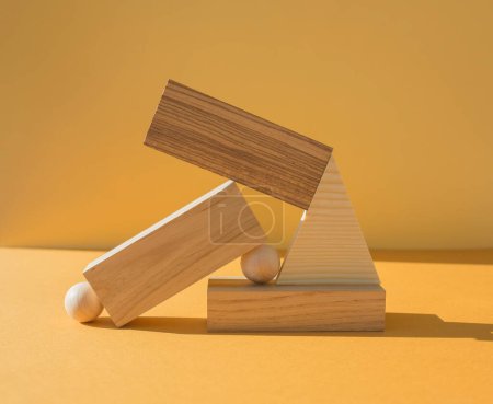 Stack of arranged wooden figures on yellow background. Balance concept.