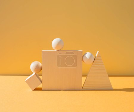Photo for Several wooden figures arranged on yellow background, hard light. Balance concept. - Royalty Free Image