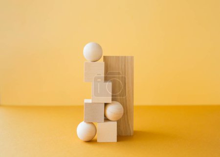 Stapel dreidimensionaler Holzfiguren auf gelbem Hintergrund. Gleichgewichtskonzept.