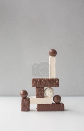 Many sweet snacks - candies, marshmallow, wafers arranged as complex vertical geometric composition. Balance concept.
