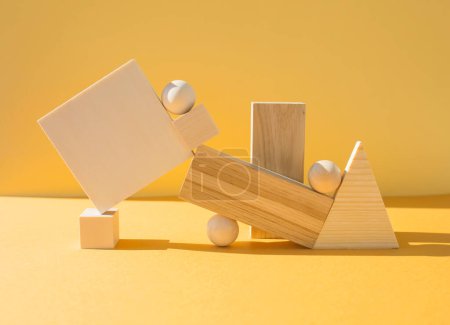 Szene mit vielen geometrischen Formen auf gelbem Hintergrund. Stapel von Holzobjekten, Balance-Konzept.