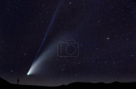 Téléchargez les photos : Silhouette de l'homme prenant une photo de comète passant entre les étoiles - en image libre de droit