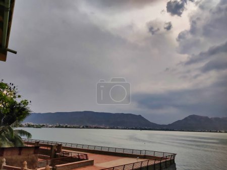 Photo for Ajmer, India Circa 2023: Picture of Lake Point View at Ana Sagar Lake. Water body with grey clouds in sky and hills in background shot on a rainy day - Royalty Free Image