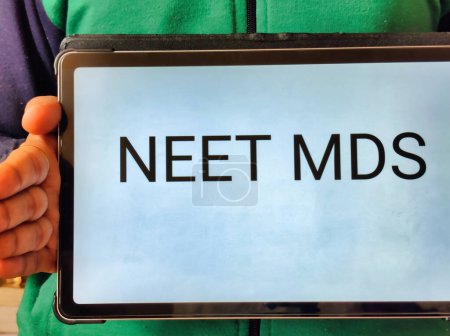 Imagen de un médico dentista sosteniendo una pancarta con NEET MDS escrito en ella