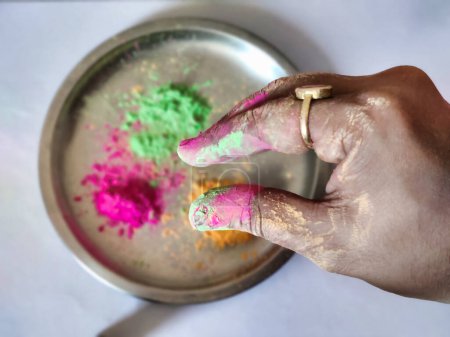 Téléchargez les photos : Photo de poudre de holi coloré sur le coup de main contre la plaque de couleur holi en arrière-plan. Festival Holi en Inde - en image libre de droit