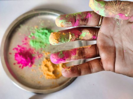 Téléchargez les photos : Photo de poudre de holi coloré sur le coup de main contre la plaque de couleur holi en arrière-plan. Festival Holi en Inde - en image libre de droit