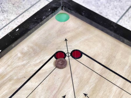 Picture of carrom coins on a carrom board shot during daylight