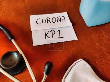 Picture of a placard with CORONA KP 1 written on it with a mask, sanitizer and a stethoscope kept on a table. Corona virus new strain. Covid-19 Infection