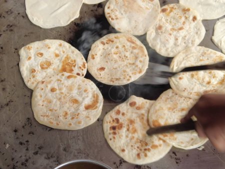 Téléchargez les photos : Cooking roti chapati on a big cooking pan , - en image libre de droit