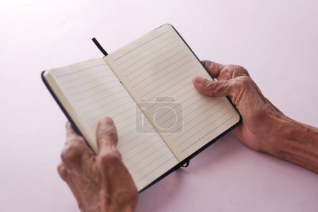 Photo for Senior women hand turning a pager of a diary . - Royalty Free Image