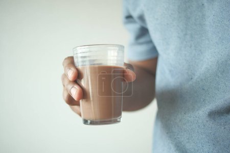 man hand holding glass of chocolate milk .