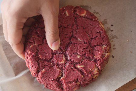  women hand creaking red velvet cookies.