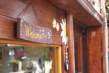 texto escrito a mano de bienvenida en papel colgado en la puerta de la cafetería .