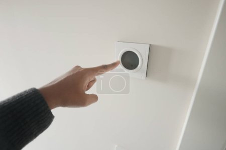 Handverstellbares Smart-Home-Thermostat an weißer Wand mit moderner Technik und Interieur