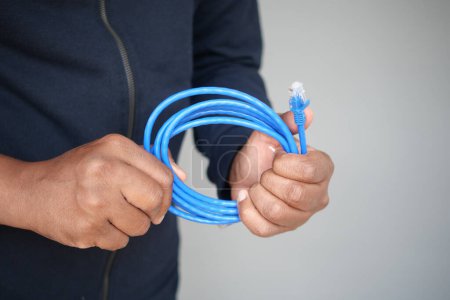 A closeup of hands holding a coiled blue Ethernet cable for a network connection.