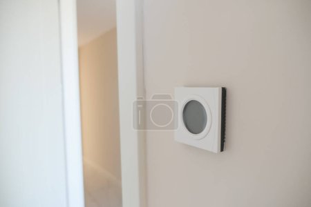  Intelligenter Thermostat an weißer Wand für optimale Kontrolle der Wohntemperatur