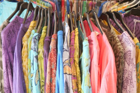 Foto de Prendas variadas y vibrantes que cuelgan en un estante de ropa en una tienda, mostrando varios colores y patrones. - Imagen libre de derechos