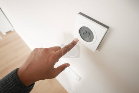 Handverstellbares Smart-Home-Thermostat an weißer Wand mit moderner Technik und Interieur