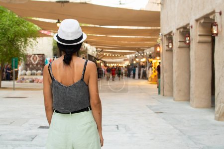 Foto de Dubái, Emiratos Árabes Unidos - 12 de octubre de 2022: paseo turístico de una mujer por el viejo Dubái explorar la zona y tiendas de recuerdos - Imagen libre de derechos