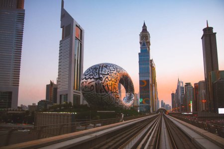 Téléchargez les photos : Dubaï, Émirats arabes unis - 10 octobre 2022 : train de métro sur chemin de fer à Dubaï avec musée du futur et coucher du soleil - en image libre de droit